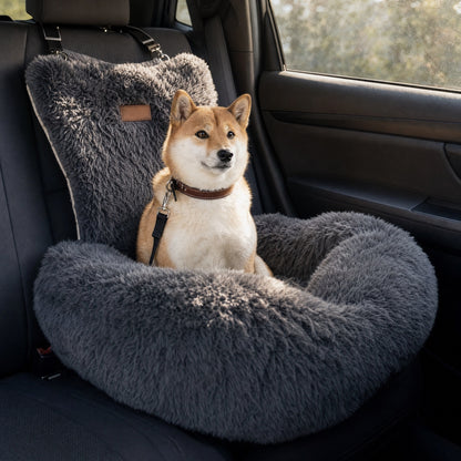 A Shiba Inu sitting upright in a charcoal grey Nordpaw lounger car bed on a car back seat